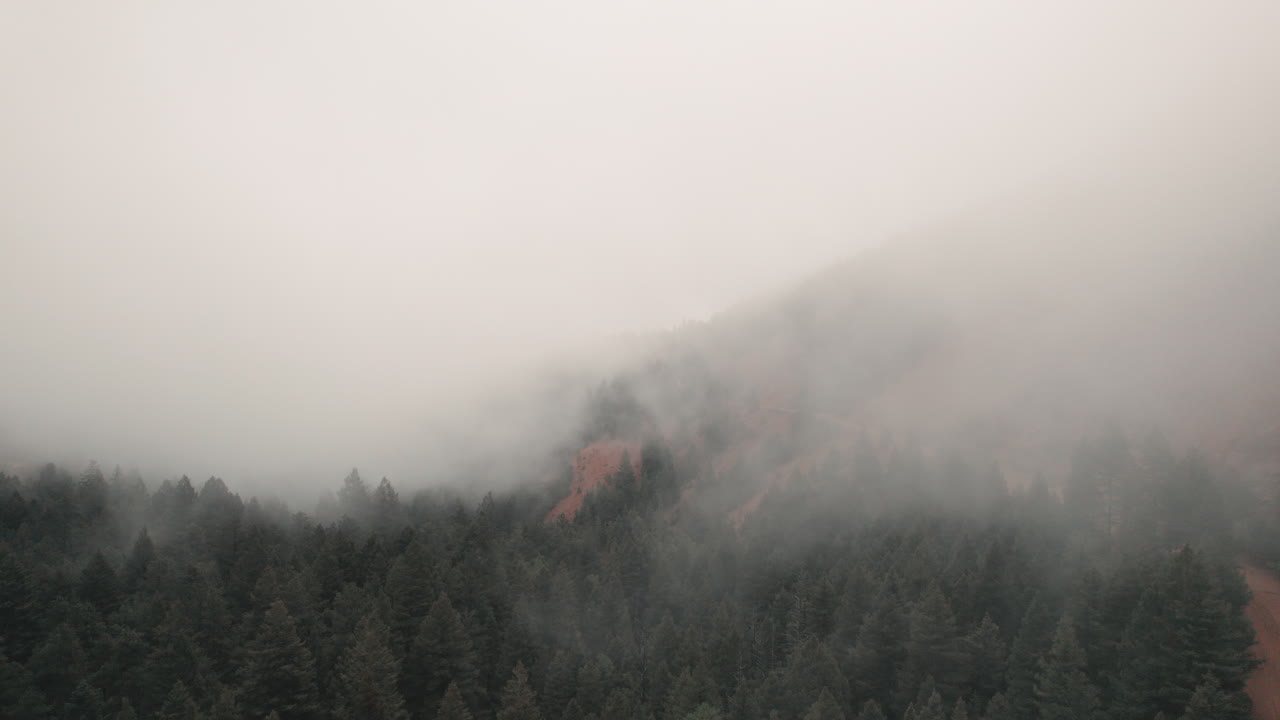 Aerial view over dirt road through thick fog, mist in Cheyenne Canyon, Colorado.