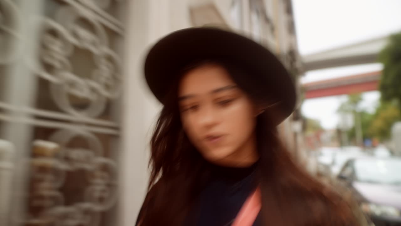 モーションブラーがかかった都会の通りを歩くおしゃれな若い女性