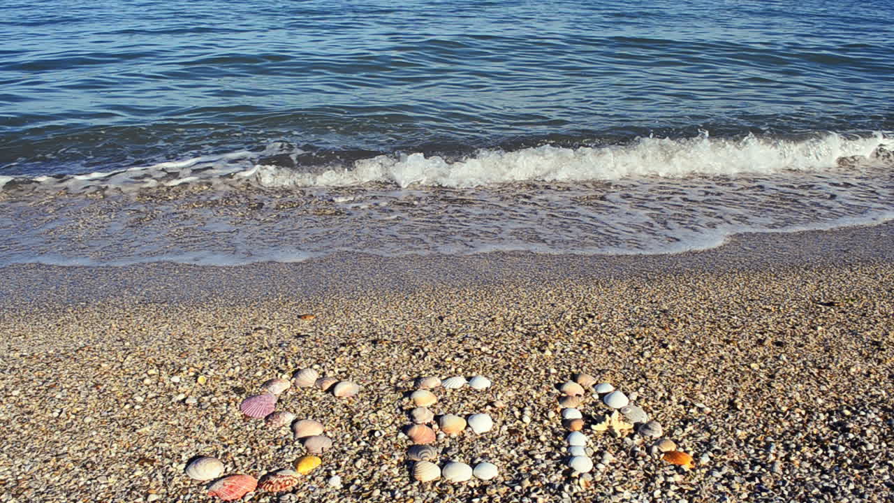 Indskrift 'hav' i sandet. Optagelse på stranden.