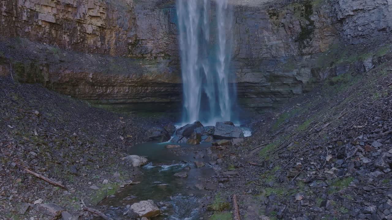 En rolig foss fosser ned en steinete klippe og ut i en liten bekk i fredelige omgivelser.