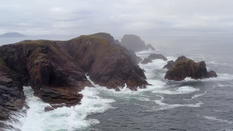 dramatic aerial of hell’s hole from the sea on a foggy morning at malin head.