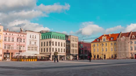 an afternoon time-lapse of people walking along the town-square of bydgoszcz, poland under sunny conditions.