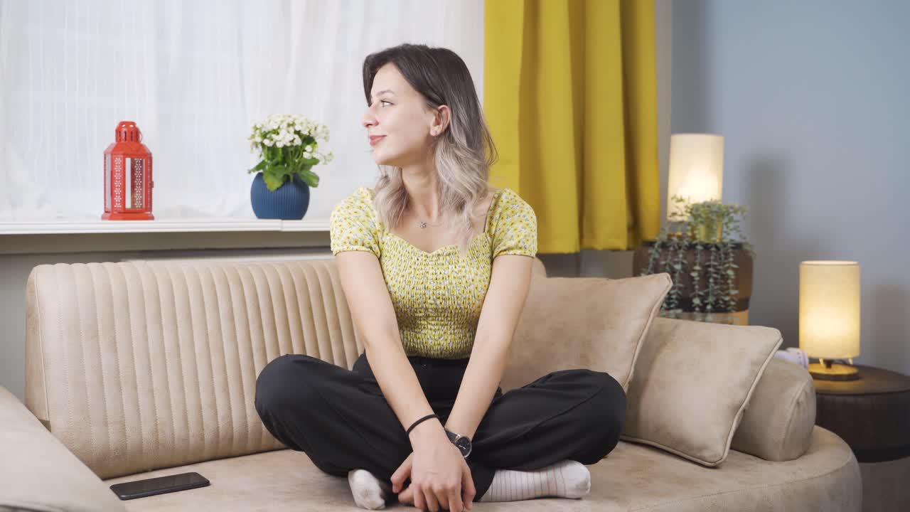 행복한 젊은 여자는 창문 밖을 바라보고 깊은 숨을 쉬고 있습니다.