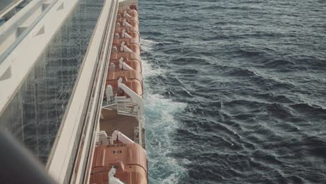 static shot of waves crashing on the side of a large cruise liner as it sails through the ocean