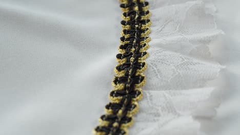 collar festivo. encaje blanco con decoración negra y dorada de primer plano. coser un vestido de novia. guipure ligero. sastrería hecha a mano, concepto de ropa profesional. fondo abstracto
