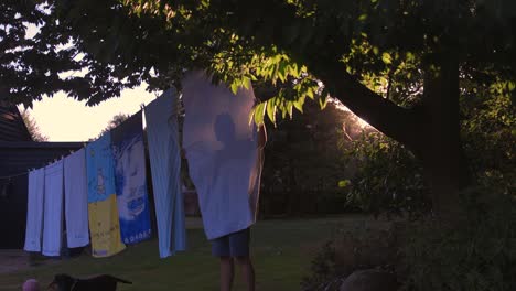 silueta de hombre colgando toallas en el tendedero al atardecer