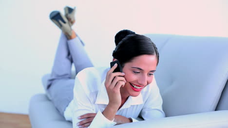 attractive businesswoman lying on couch and speaking on the phone