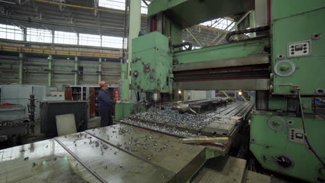 machinist working on a large milling machine in a factory