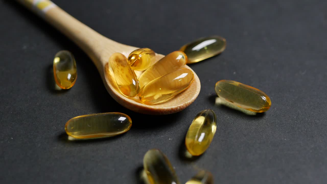 cápsulas de aceite de pescado en cuchara de madera