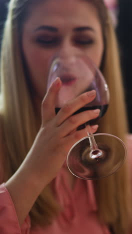 cheerful woman with salad enjoys delicious red wine and smiles to partner during conversation at table at festive dinner at home closeup slow motion