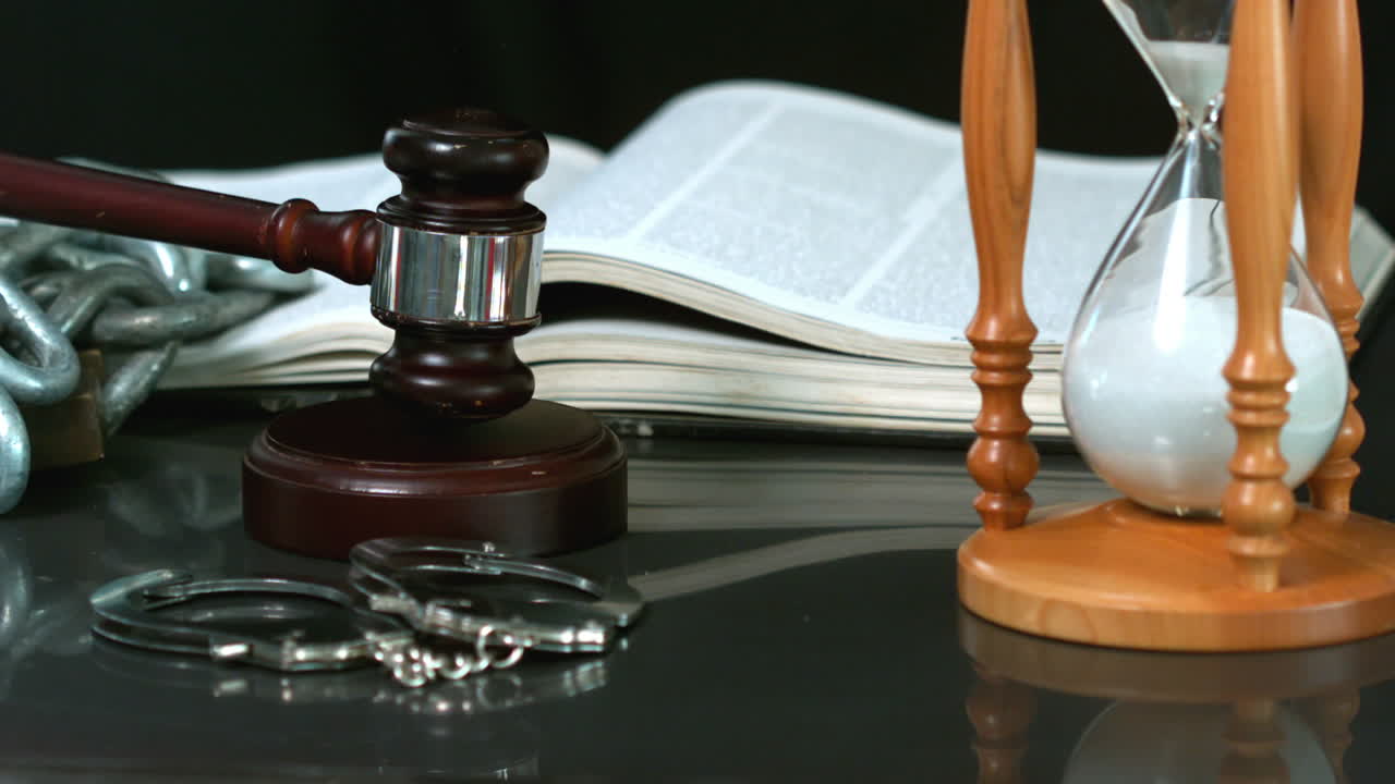 martillo cayendo en el bloque de sonido al lado de reloj de arena biblia y esposas