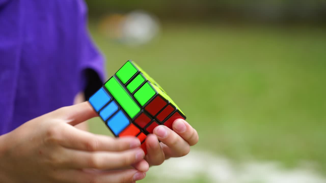 Close-up video of solving Rubik's cube. Hands of a boy shows quick combination of Rubik's cube solving puzzle to the end. Problem solving game.