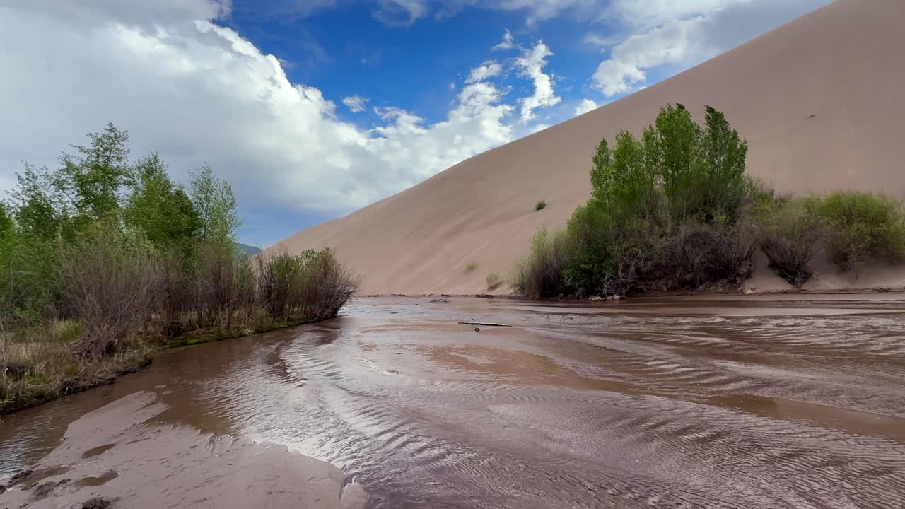 Medano Creek river landscape Great Sand Dunes National Park Sangre de Cristo range Rocky Mountains spring summer sunny clouds blue sky Colorado unique magical large amounts of sand dune windy pan