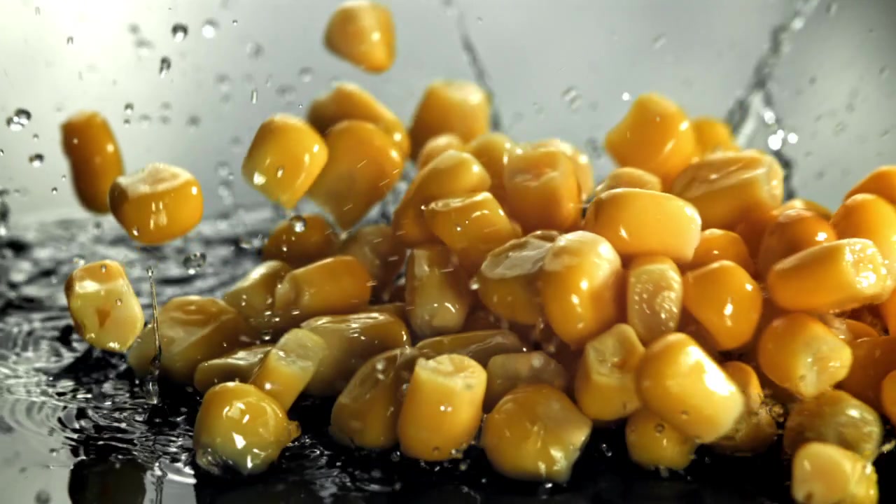 Fresh Corn Kernels Falling and Splashing into Water in Slow Motion