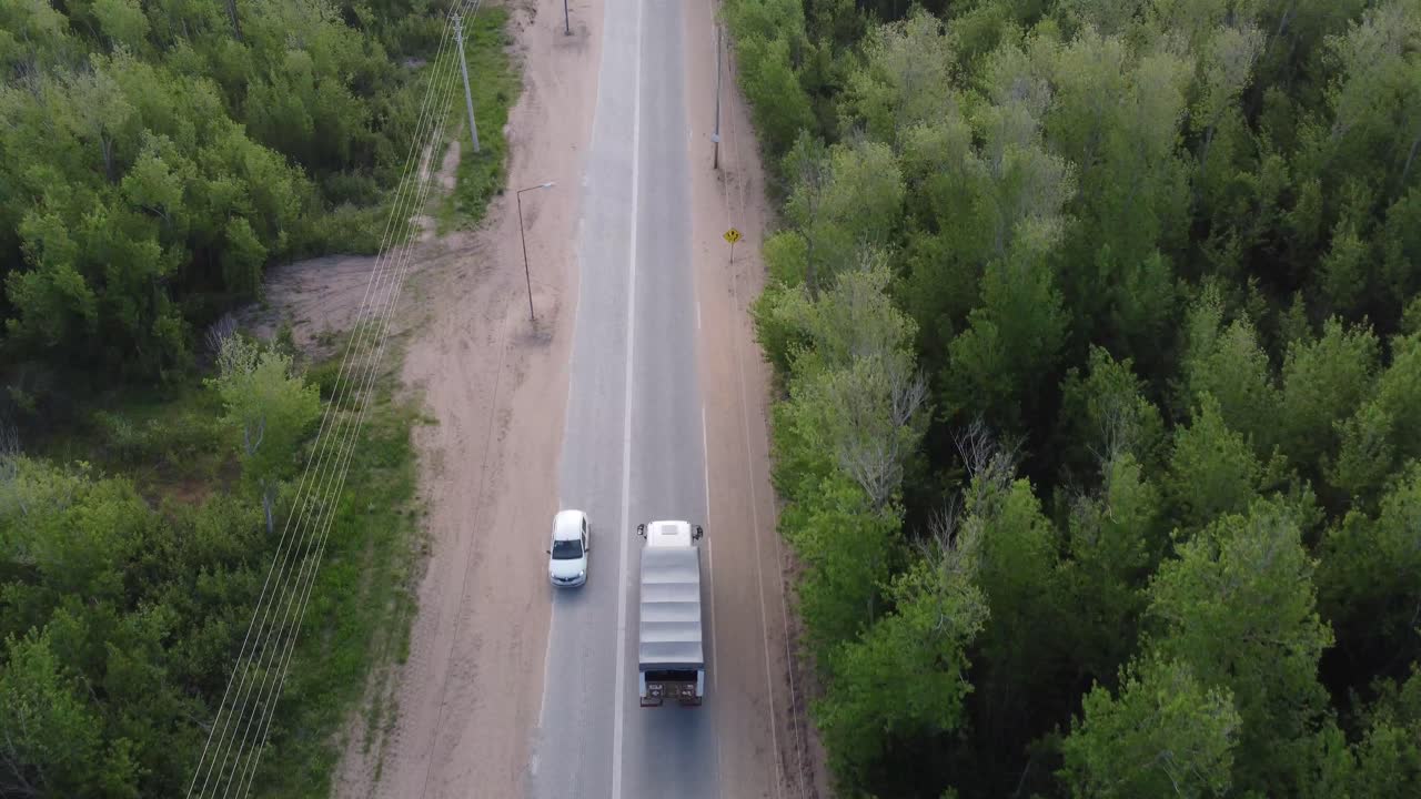 Vista aerea di un camion in movimento su una strada rurale in Argentina, circondato da alberi di una fitta foresta verde durante il giorno.