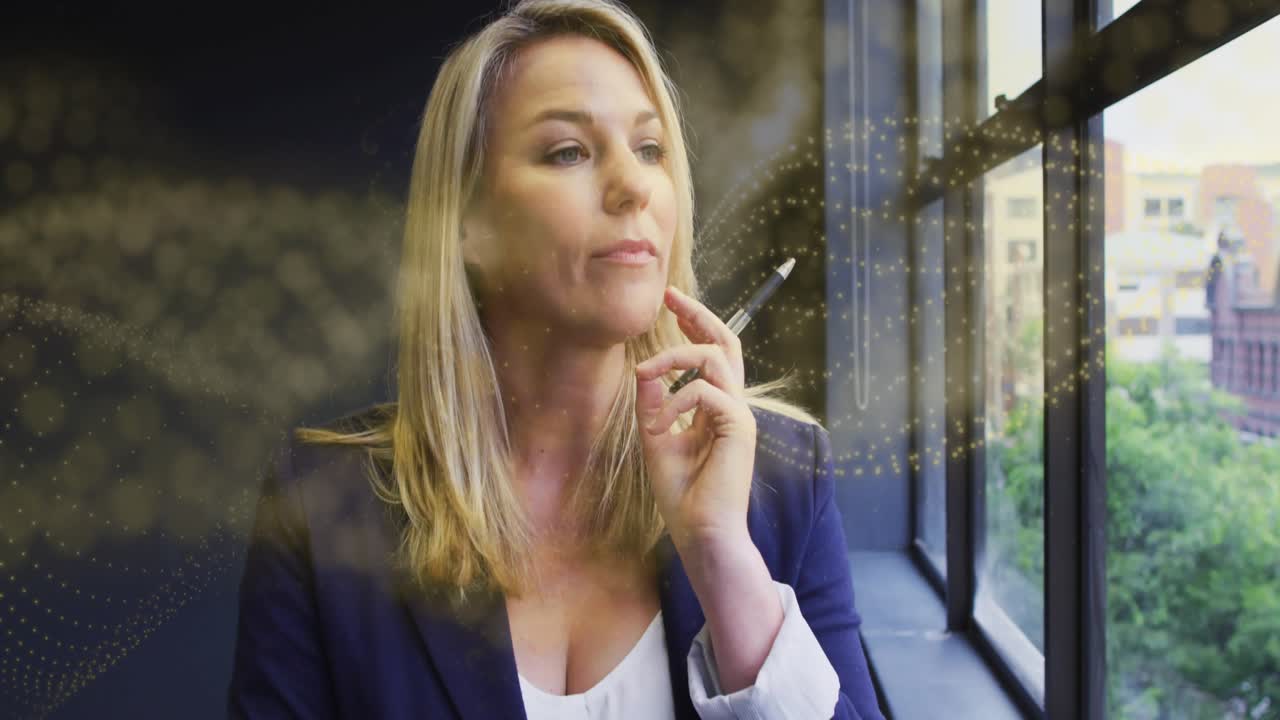 Businesswoman pressing pen against chin reflecting gazing out window, golden particles overlaying
