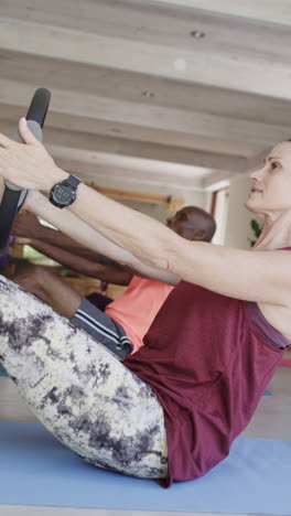 vertical video of senior diverse people exercising with female coach in slow motion