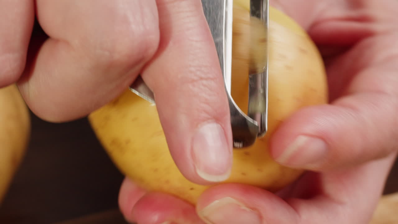 Close-up of Hand Peeling a Fresh Potato with a Peeler