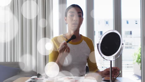 animación de manchas de luz sobre una mujer biracial aplicando maquillaje.