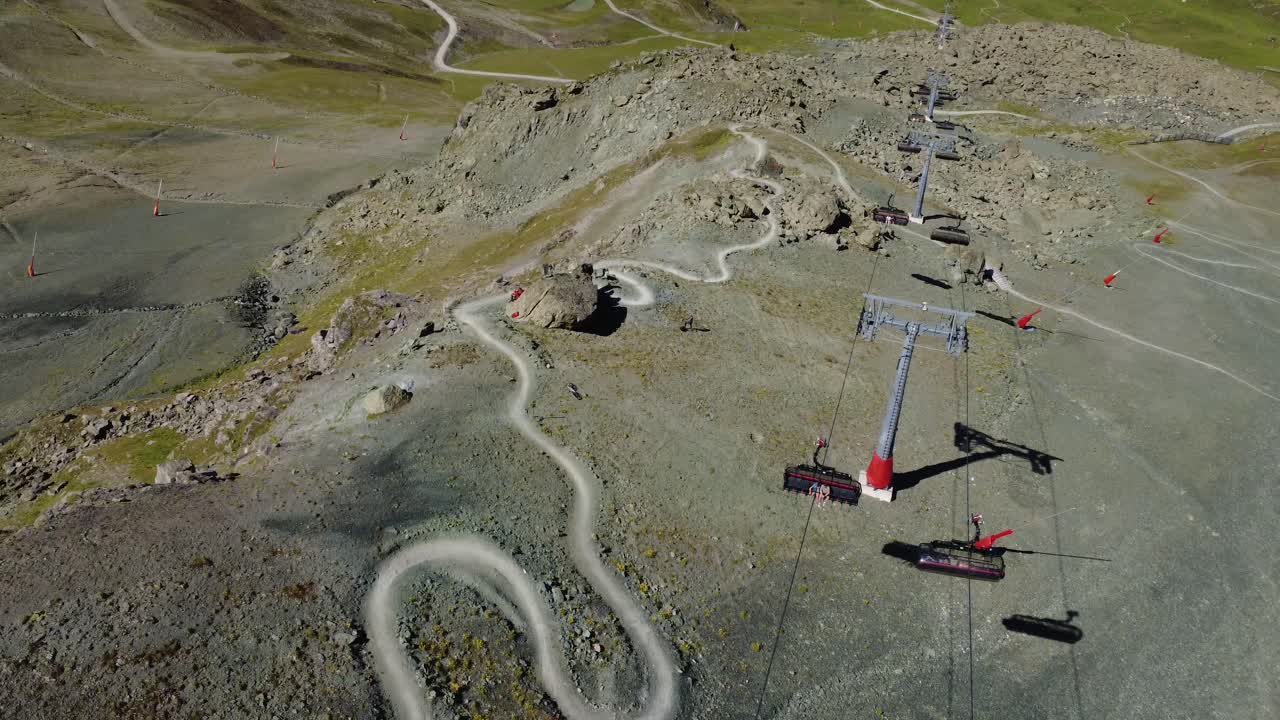 Drone footage showing a mountain bike trail intersecting with a gondola lift above in the Alps. Perfect for tourism, sports and travel concepts