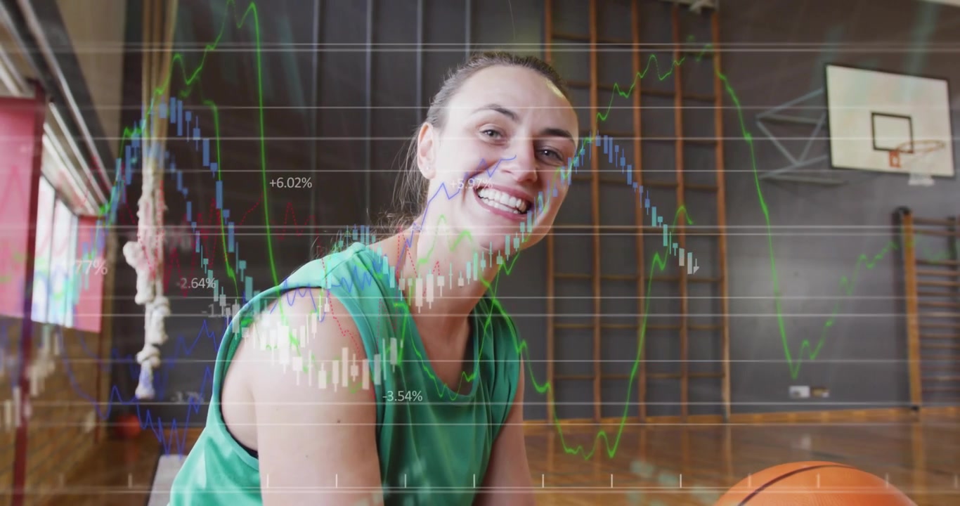 La telecamera arretra, mostrando una donna che fa ruotare un pallone da basket su una panca, mentre grafici finanziari si muovono sullo schermo, in un contesto di formazione.