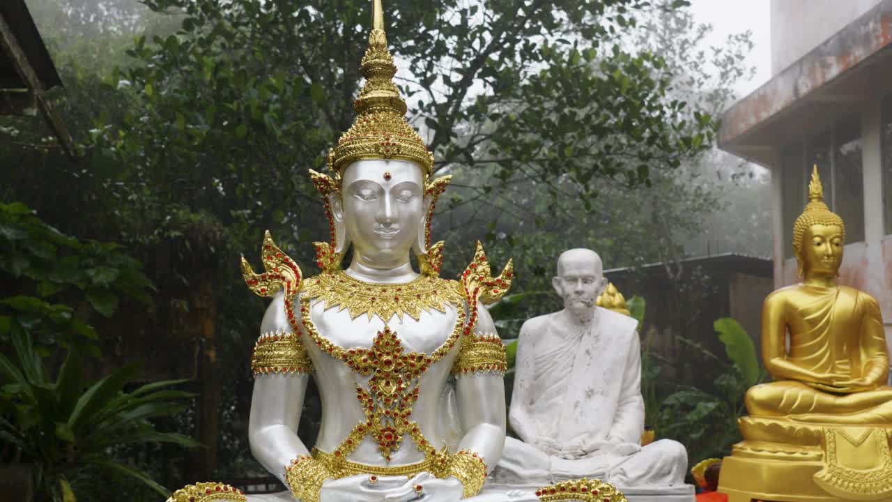 statues of divinities, buddha and priest in yoga posture outdoors in foggy weather