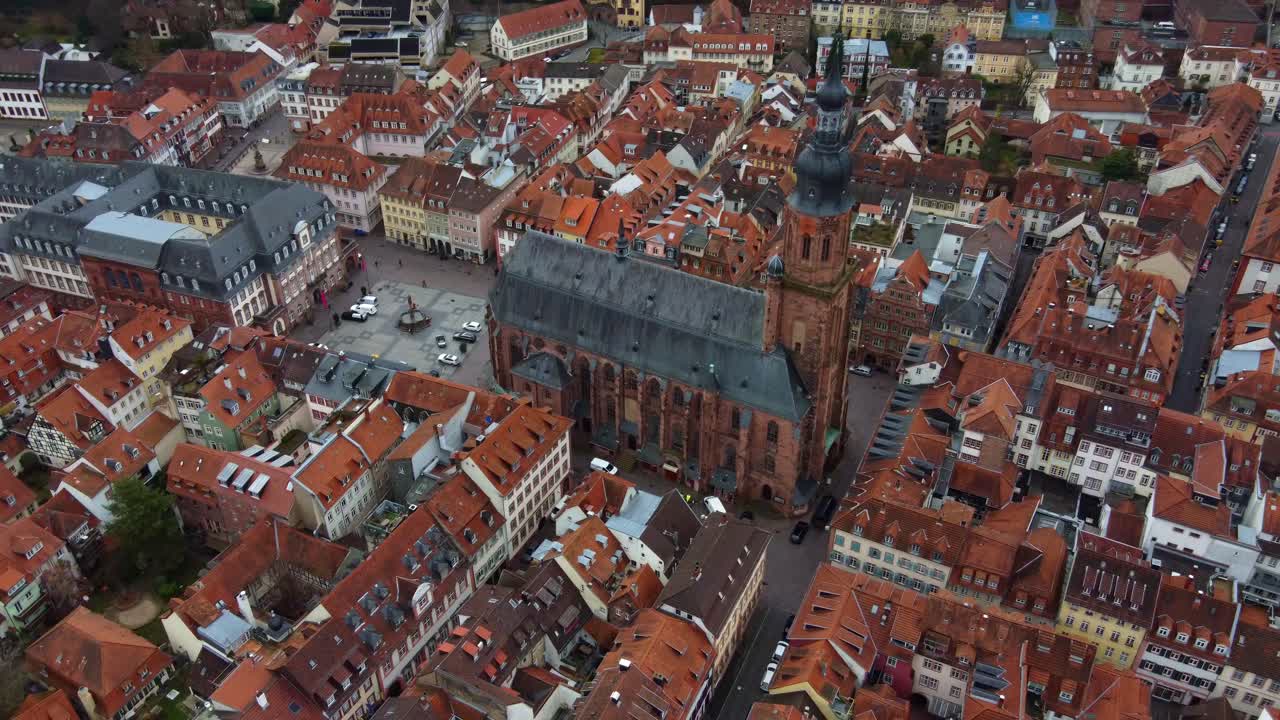 Medieval church and red brick rooftops in old town square of Heidelberg city, Drone view