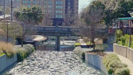 car traveling over a concrete bridge over a canal camera zooming out slowly lily pads floating on the river