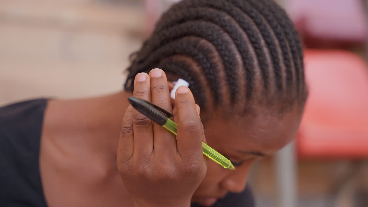 Apprenant concentré dans un moment intense. Jeune personne faisant preuve de concentration sous pression. Étudiant anxieux avec casque et stylo montrant de la tension pendant la préparation d'examen dans un environnement de stade.
