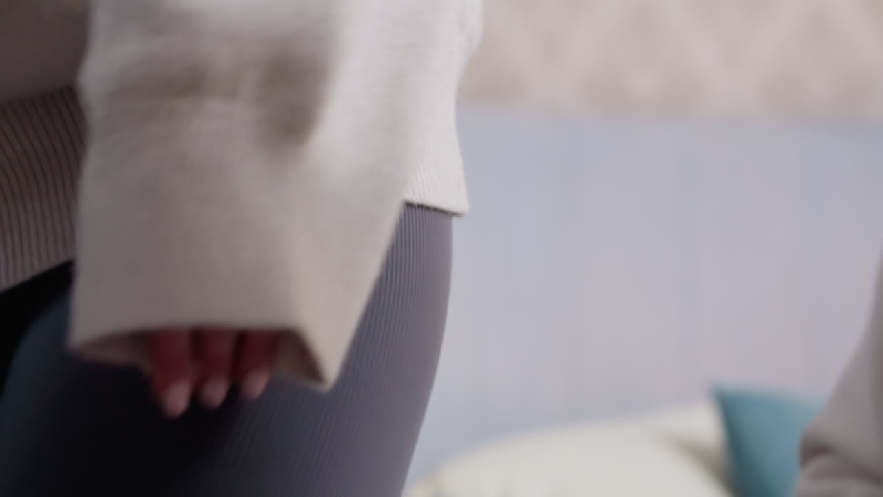 Close up of fabric texture showing soft beige material from sweater sleeve with natural folds, cozy clothing detail, warm textile surface, minimalistic fashion element highlighting casual indoor