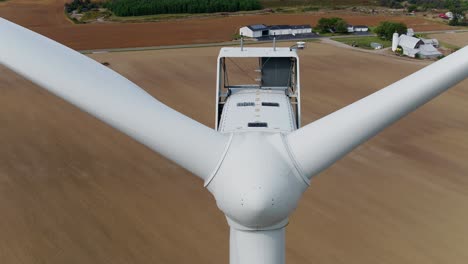 turbina eólica de primer plano disparada con un dron aéreo que asciende sobre el campo de trigo en el fondo