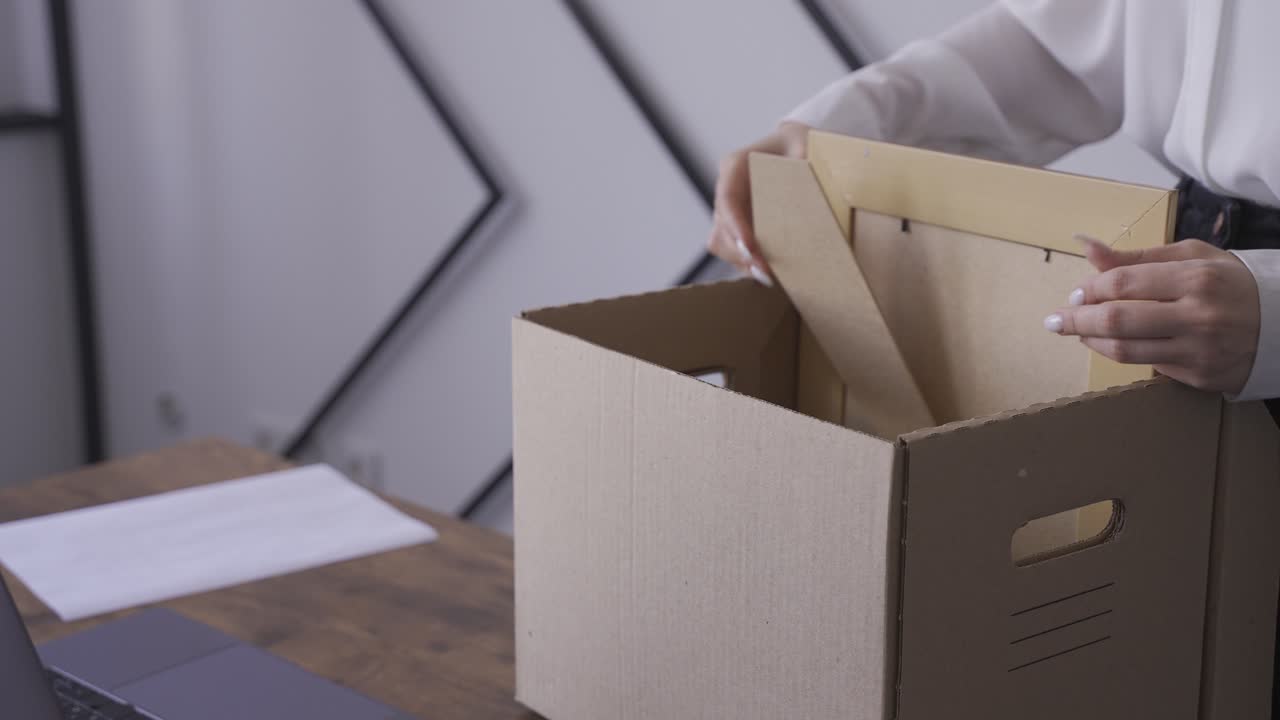Close-up of woman's hands collecting her things in a box. She is quitting her job.