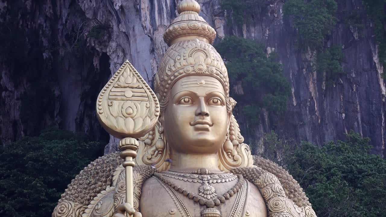 una estatua gigante de oro cerca de las cuevas de batu en malasia justo después del amanecer