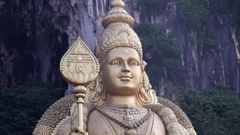 una estatua gigante de oro cerca de las cuevas de batu en malasia justo después del amanecer