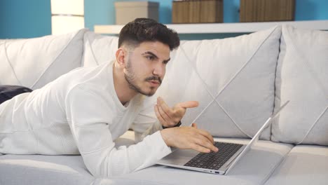 un joven que piensa y calcula, sonríe y escribe en la computadora portátil.