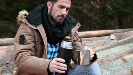 hombre guapo bebiendo té o café en el bosque de otoño