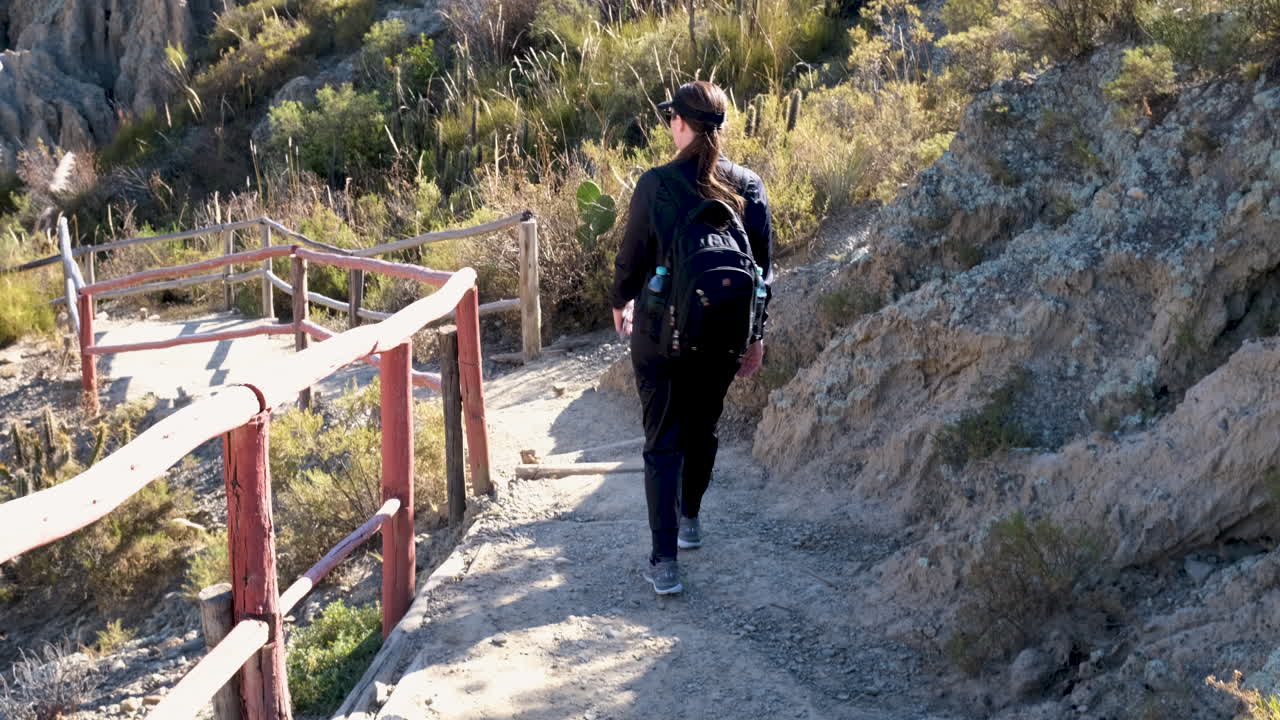 Landscape view of female tourist with backpack walking down outdoor trail pathway stairs to Valle de la Luna landmark attraction rock formation in Mallasa La Paz city Bolivia adventure sightseeing