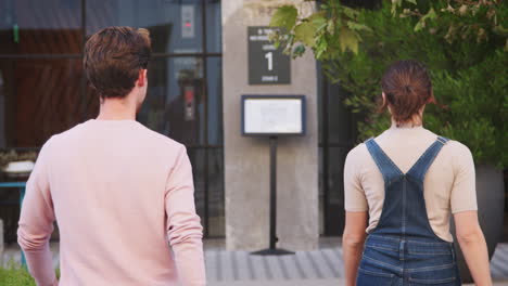 millennial hipster couple walking across the road in the city, back view