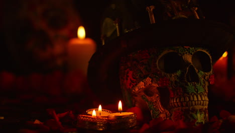 still life of decorated skull wearing hat surrounded by candles celebrating mexican holiday of dia de muertos or day of the dead