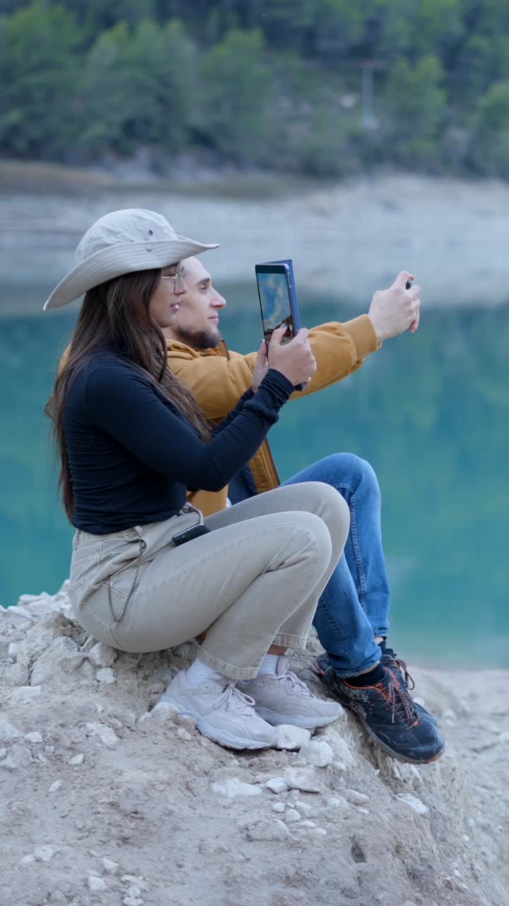 Couple taking photos by a lake