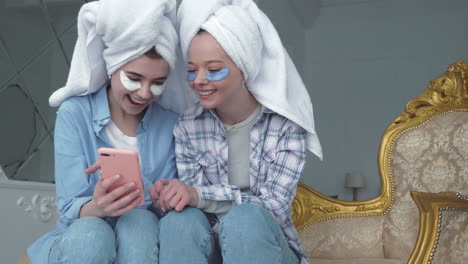 dos amigos disfrutando de una sesión de cuidado de la piel y mirando un teléfono