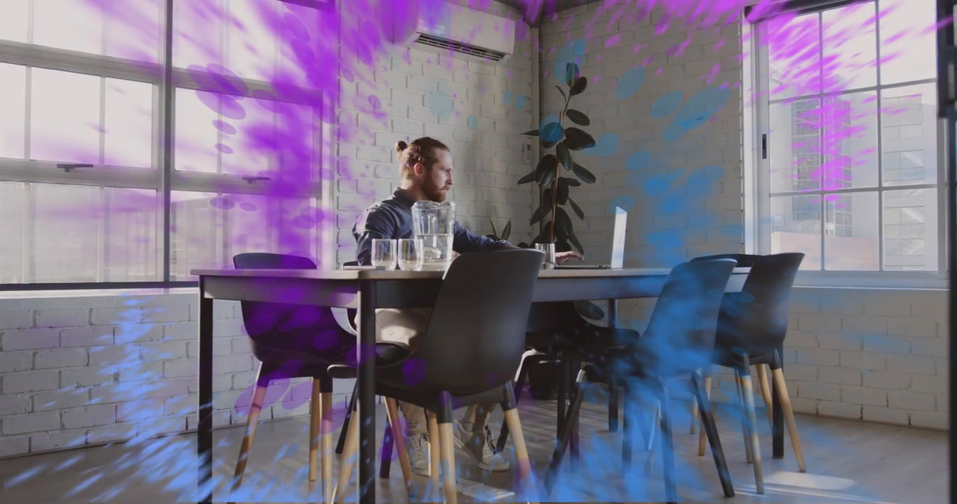 Mid adult man typing at laptop and initiating swirling blue purple mist vortex for tech demo
