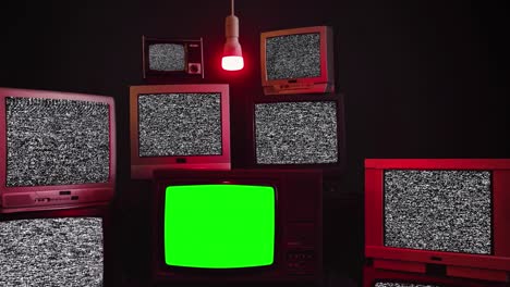 tv retro impilate che accendono schermi verdi. tono sepia.