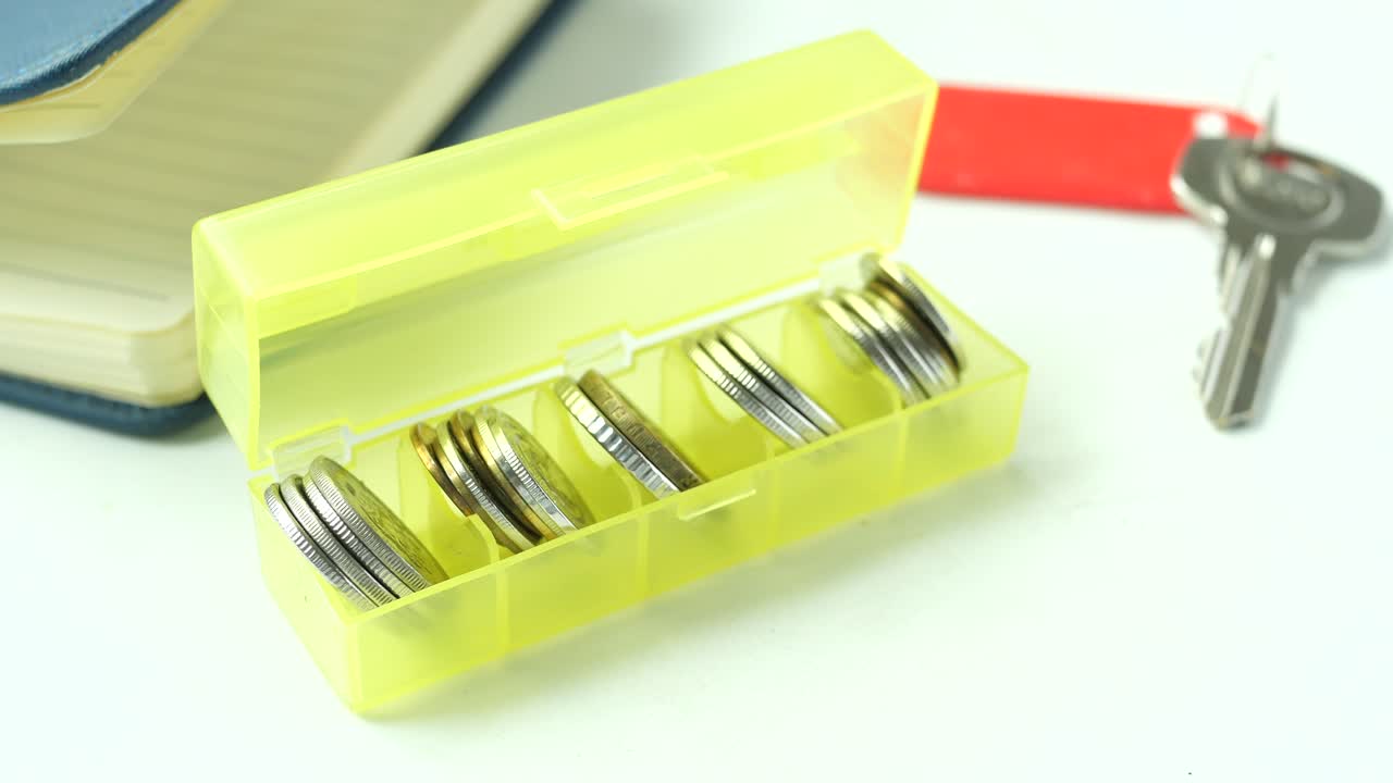 노란색 배경 에 있는 플라스틱 상자 에 있는 동전 들 의 클로즈업