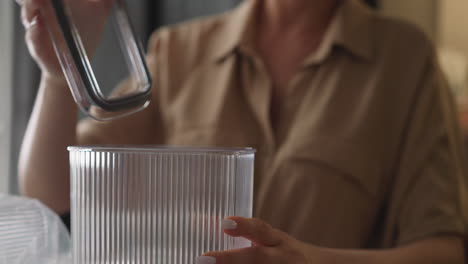 young lady removes lid from transparent plastic food container