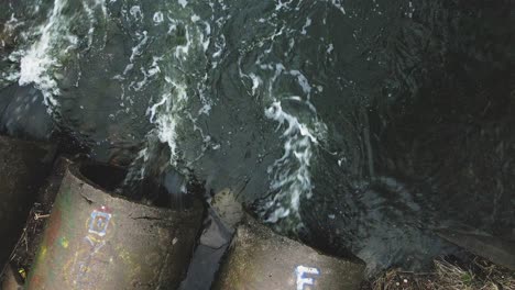 flying over concrete sewers. streams of water flow through concrete pipes. polluted body of water in the park. camera down.