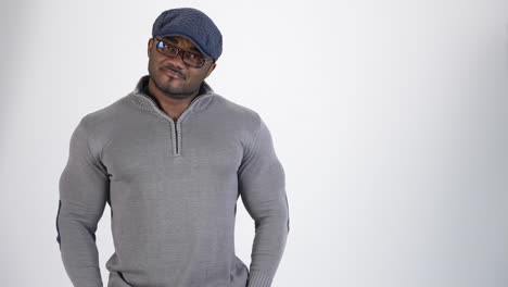 smiling afro american athlete in studio. portrait of a sportive guy with black skin in gray sweater and blue cap looking on camera. copy space.