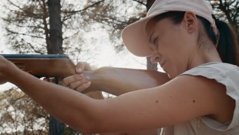 handheld close up of young woman reloads air rifle and fire to target on sunset