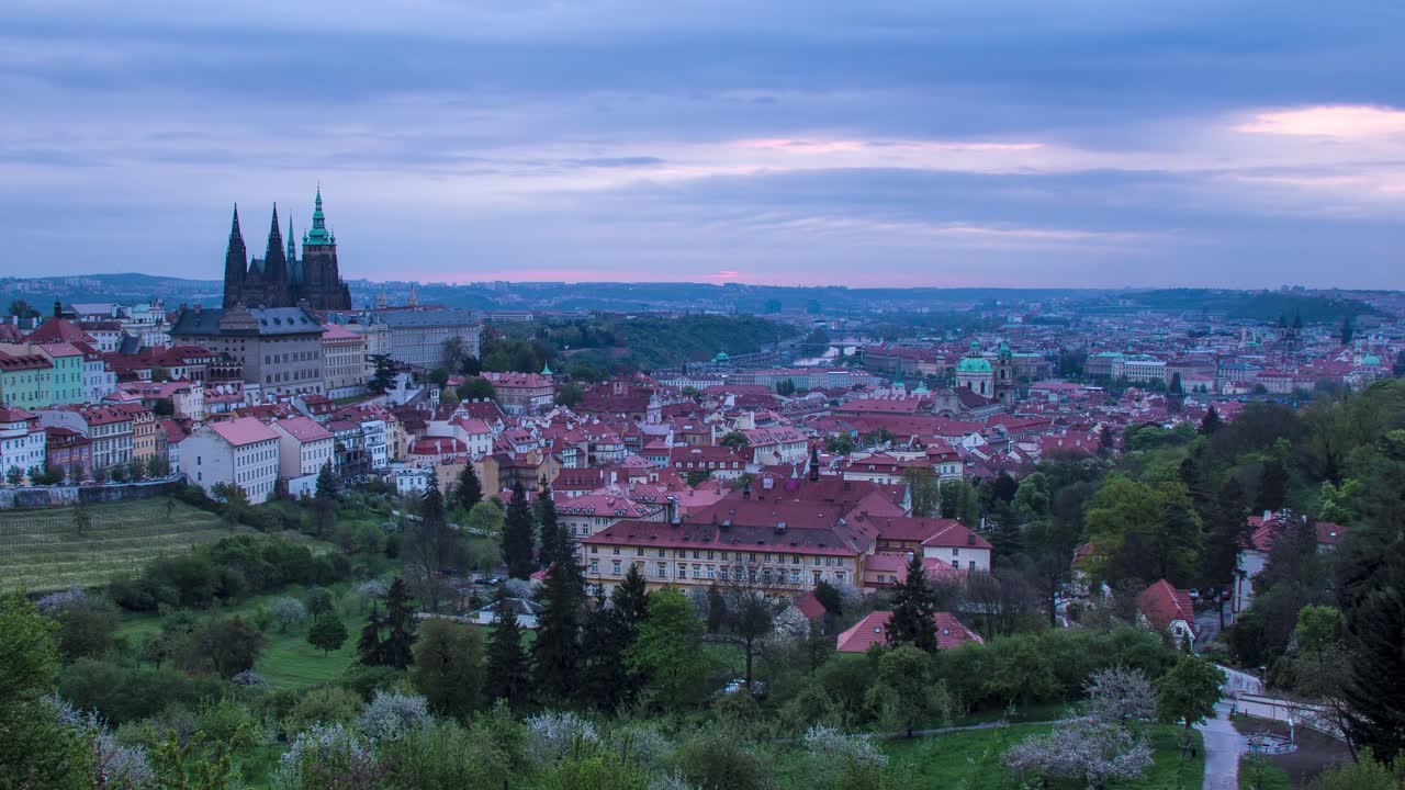Night to day sunrise timelapse in Prague, Czech Republic as seen from Strahov gardens with view of Prague Castle, Malá strana and downtown in the distance as the morning sunshine lights up the city