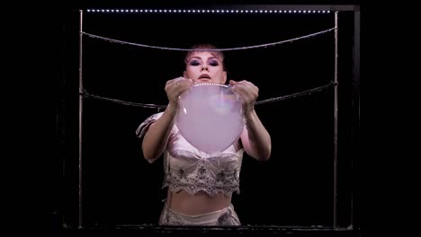 young girl does tricks with soap bubbles. she takes with her hands a big bubble with smoke inside and pierces it